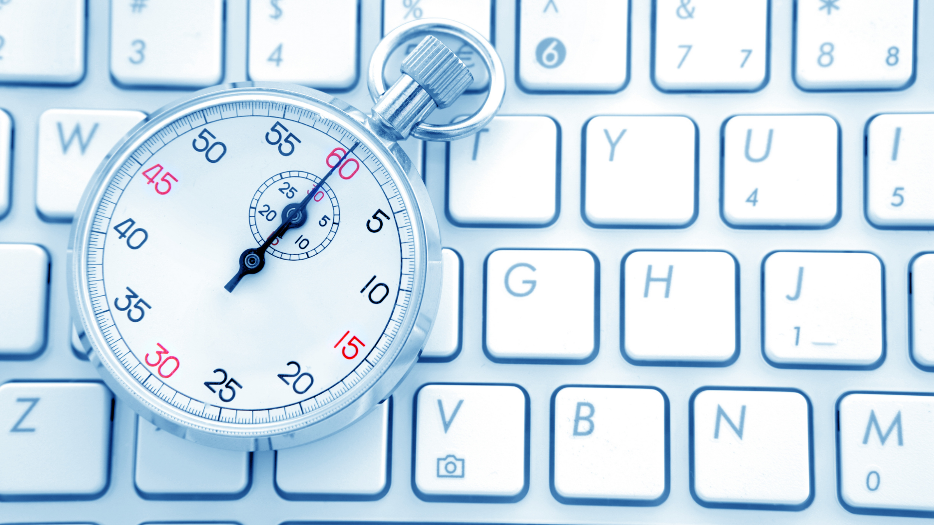 Classic silver stopwatch resting on top of a white computer keyboard